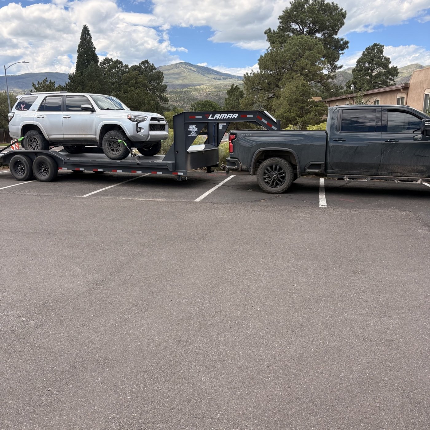 BK Hauling & Clearing work truck with a Lamar gooseneck trailer hauling a Toyota 4Runner