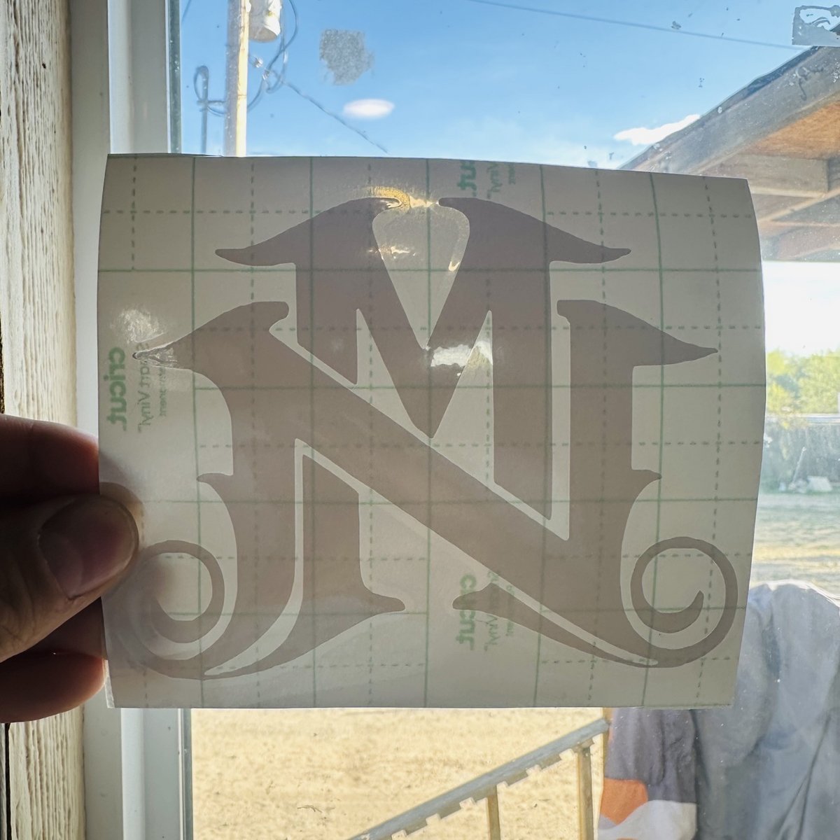 White vinyl decal with an NM monogram on transfer tape, made by KB Custom Creations