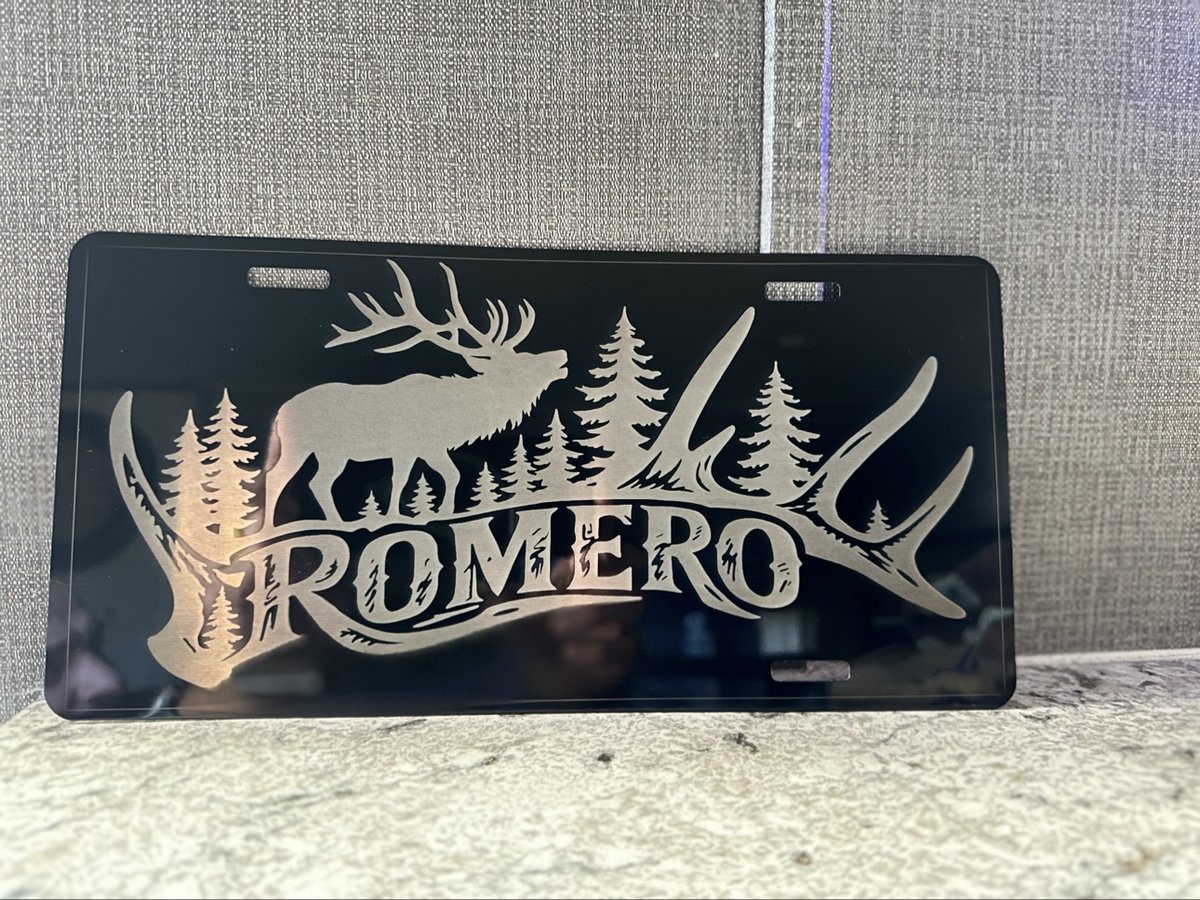 Black engraved license plate with an elk, pine trees, and antlers over a family name, by KB Custom Creations